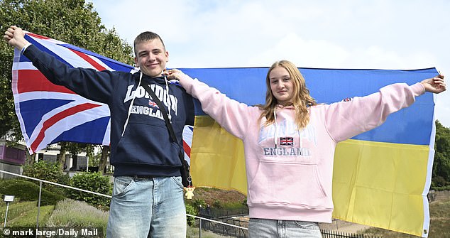 Denys and Kseniia hold flags of the UK and Ukraine at the Tower of London