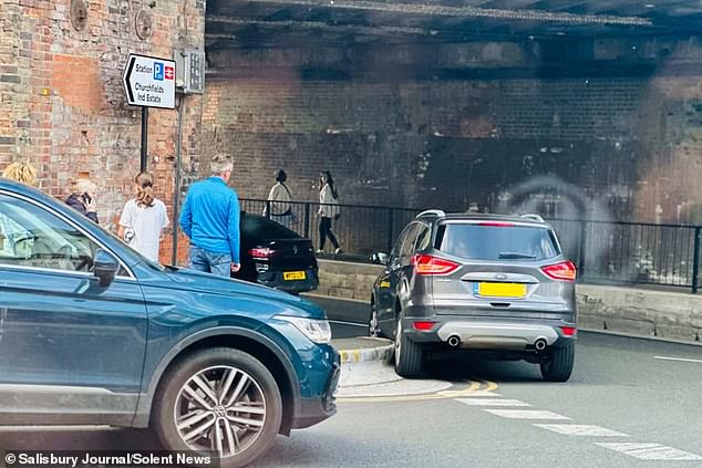 Drivers in Salisbury, Wiltshire, have waged war with their council over the 13-inch high kerb which has resulted in damage to their vehicles and the roadside. Pictured: A car can be seen struggling to drive around the kerb