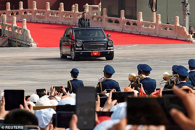 Chinese President Xi Jinping stands in a car to review the troops during a military parade