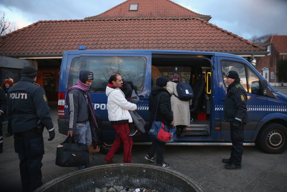 Danish police escorting a Syrian family seeking asylum into a van.