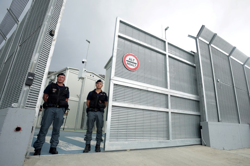 Two police officers stand guard at the entrance to a migrant center.
