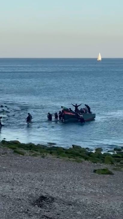 Migrants arriving by boat on a beach.