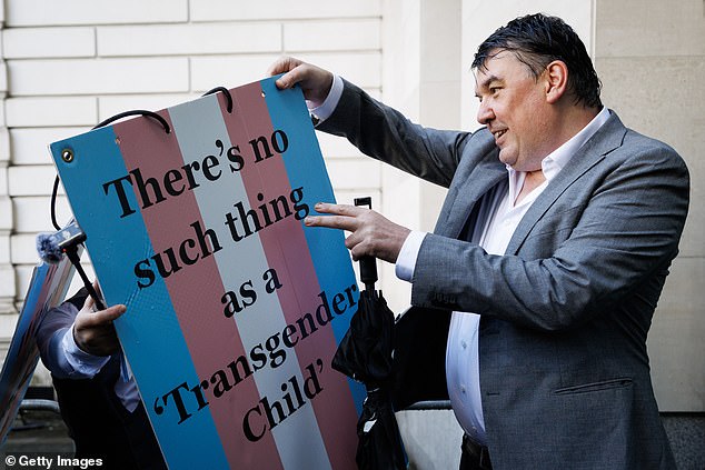 Linehan holds up a placard, which was adorned in the transgender flag colours, outside Westminster Magistrates' Court