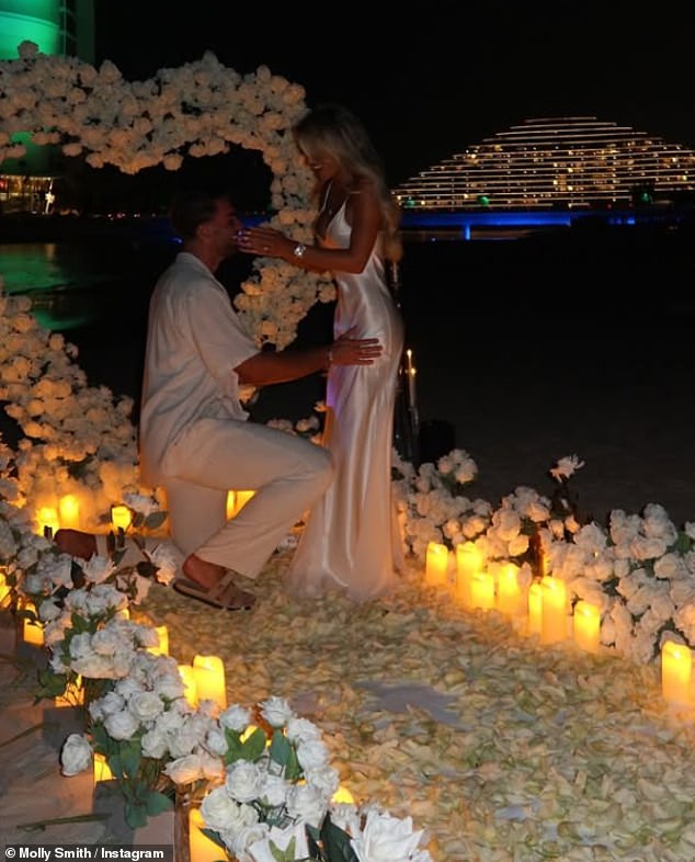 Molly, 31, looked gorgeous in a white silk dress as she showed off the sparkling ring while surrounded by candles and white flowers