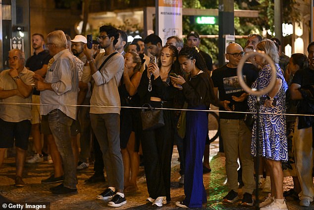 People stand behind the police line of Gloria funicular derail site