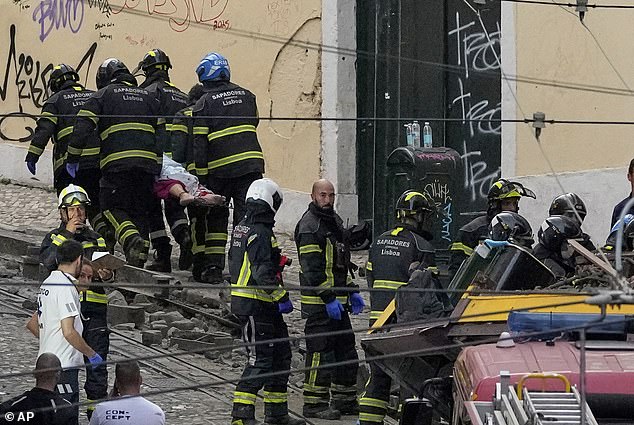 Firefighters carrying an injured person on a stretcher at the site of a derailed electric streetcar in Lisbon, Portugal