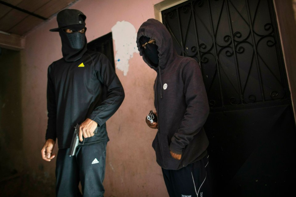 Masked criminals who go by the name "El Negrito," right, and "Dog," and are members of the Crazy Boys gang, hold their guns at their safe-house in the Petare slum of Caracas, Venezuela, Monday, May 13, 2019. Dog said he has no trouble finding ammunition for his guns on the black market, but that the challenge is paying for them in a country where the average person earns $6.50 a month. A pistol used to cost one of these bills, he said, crumbling up a 10 bolivar bill that can no longer be used to buy a single cigarette. Now, this is nothing. (AP Photo/Rodrigo Abd)