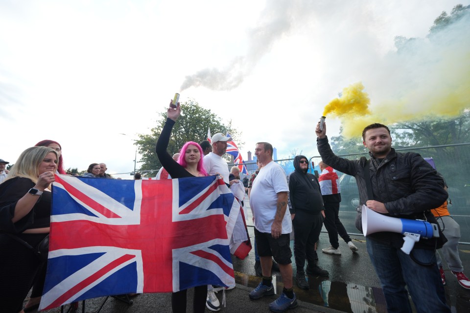 Protestors holding Union Jack flags and smoke flares outside a hotel housing asylum seekers.