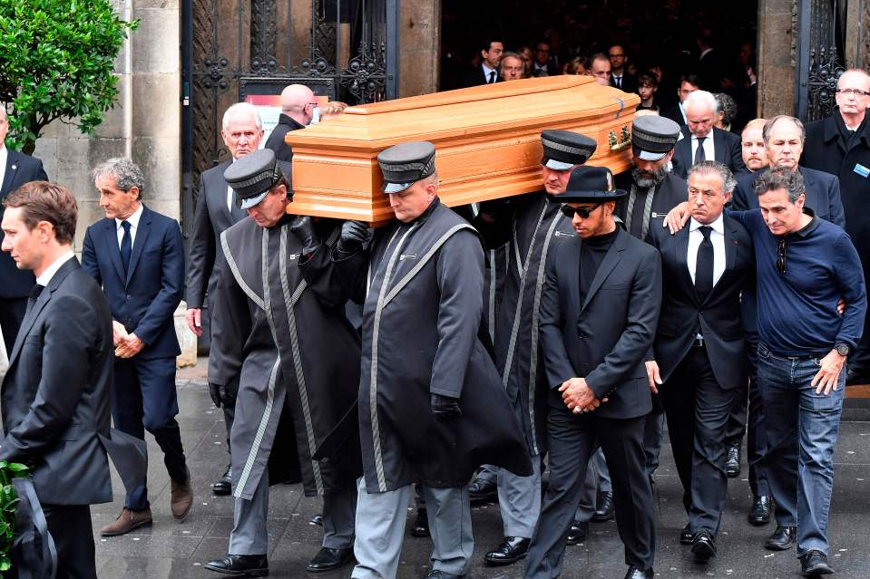 Pallbearers carry Niki Lauda's coffin from St. Stephen's Cathedral, with Alain Prost and Lewis Hamilton in attendance.