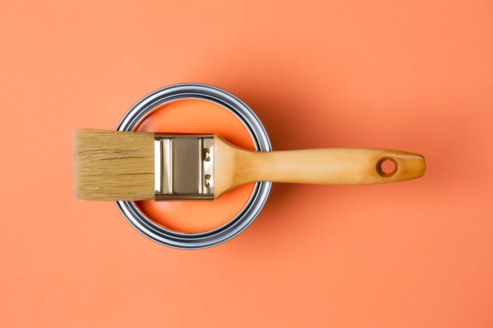 Paintbrush in a can of orange paint.