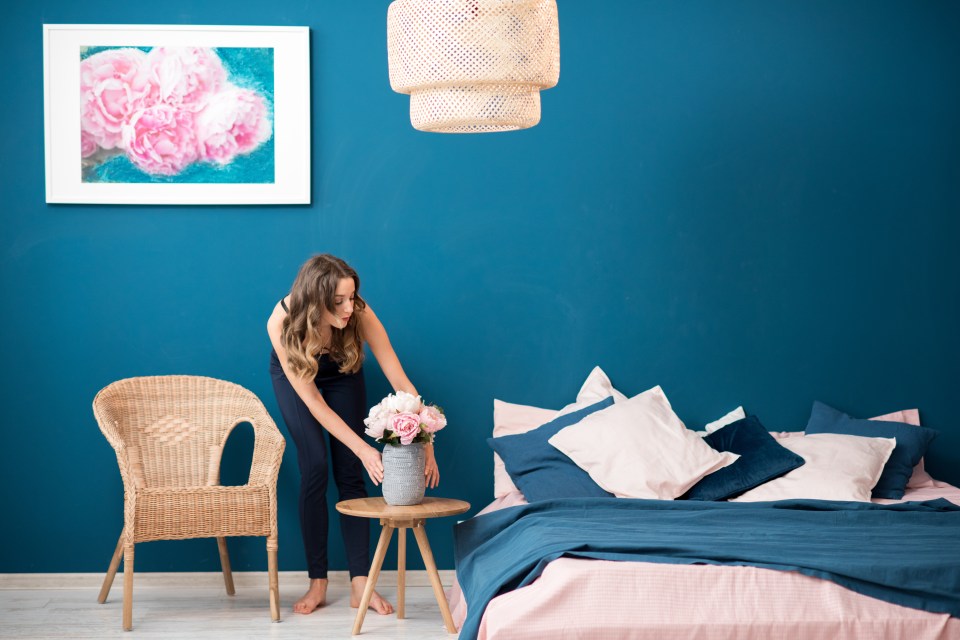 Woman arranging flowers in a bedroom.