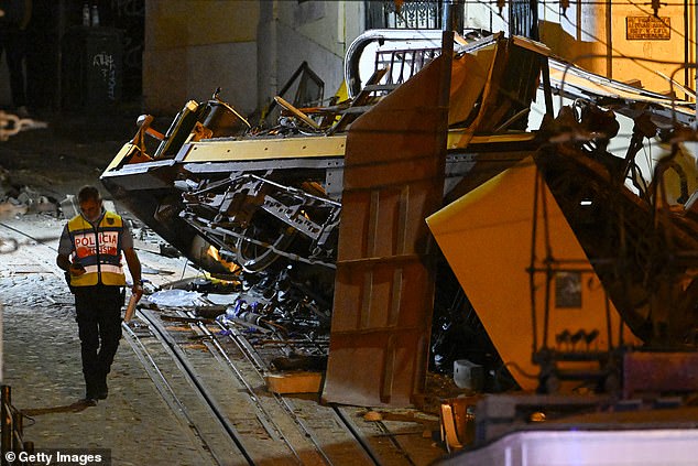 A police officer walks past the remains of wrecked Gloria funicular at derail site, September 3