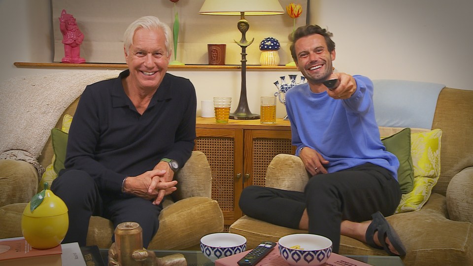 Two men sitting on a couch, one holding a remote.
