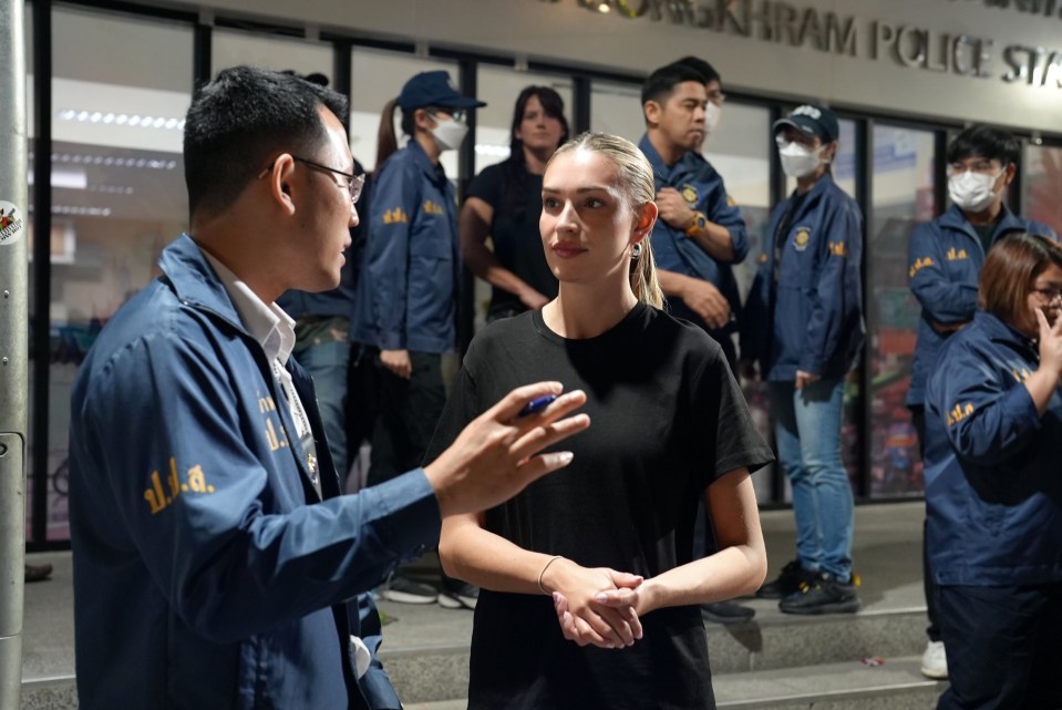 A woman speaks with a police officer outside a police station.