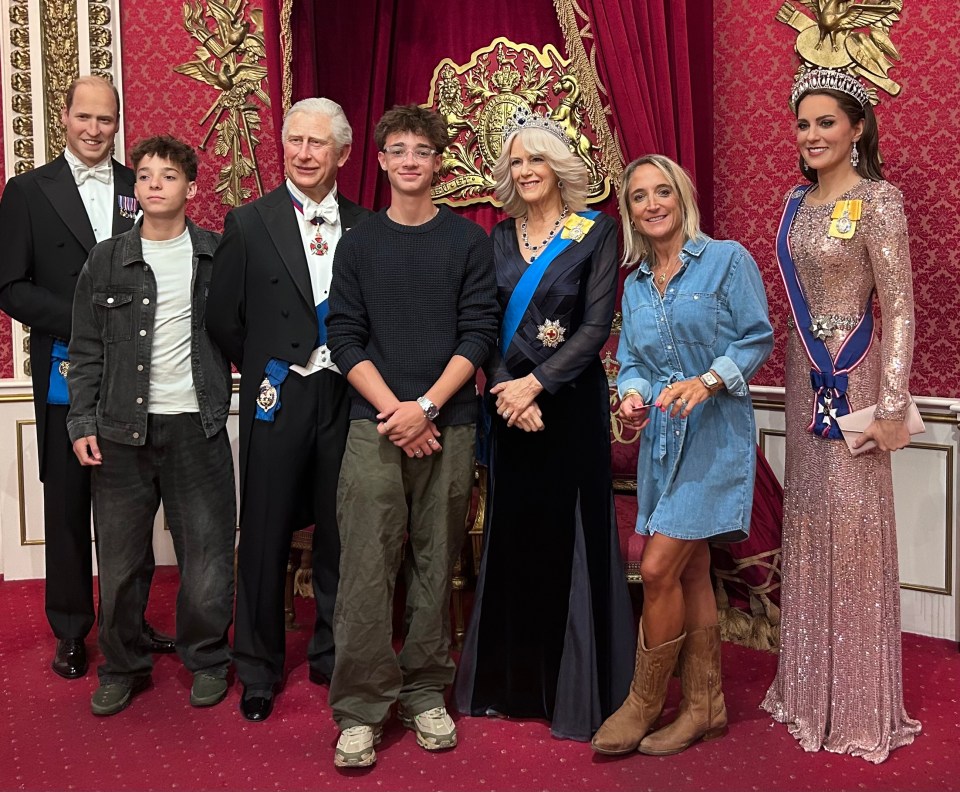 People posing with wax figures of the British Royal Family at Madame Tussauds.