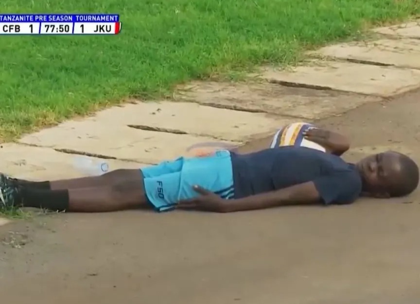Soccer player lying on the ground during a match interruption caused by a swarm of bees.