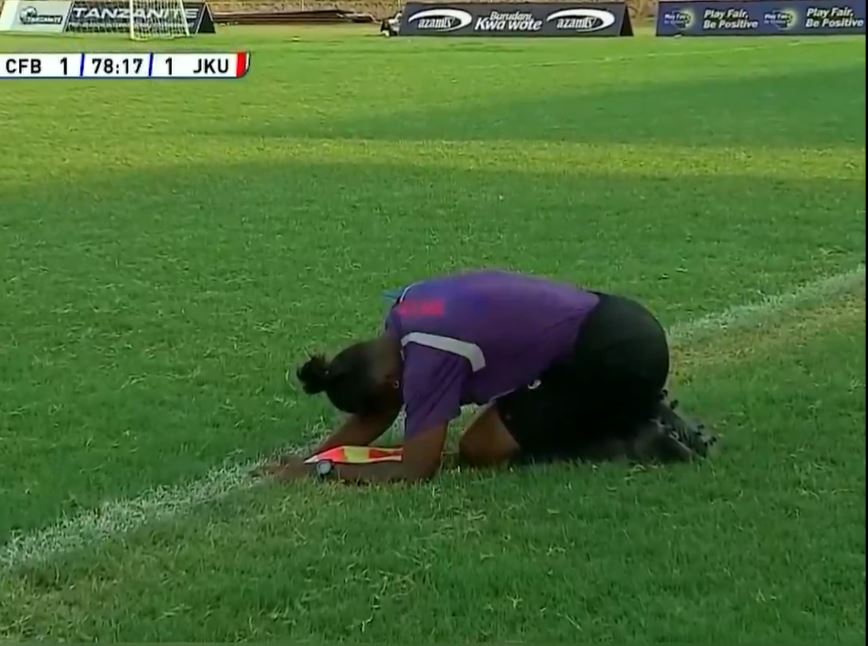 Referee kneeling on soccer field.