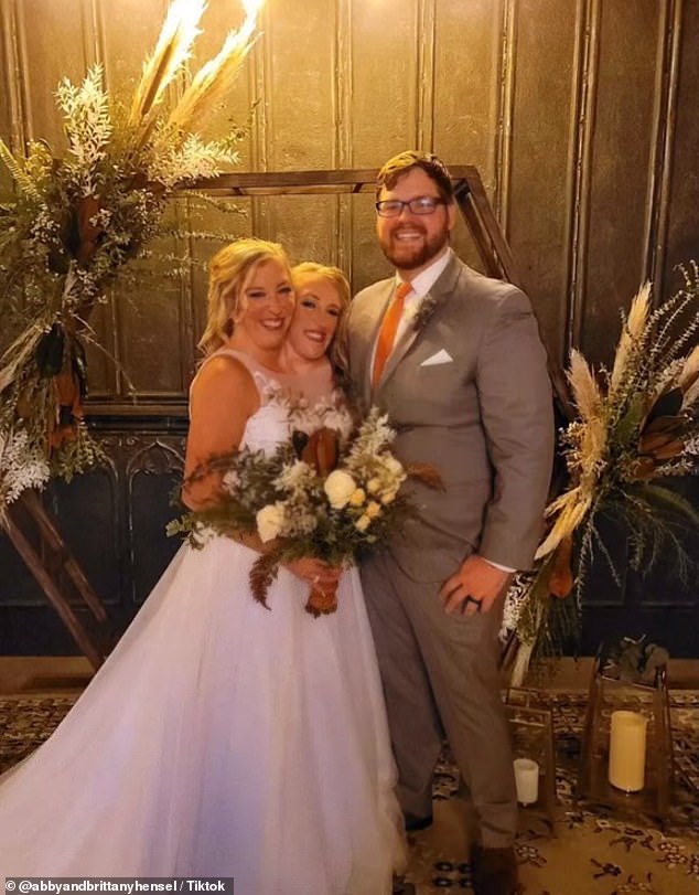 Another image shows the trio smiling post-ceremony, the twins holding a large bouquet of flowers. The post was simply captioned: '#abbyandbrittany #twins #marriage'