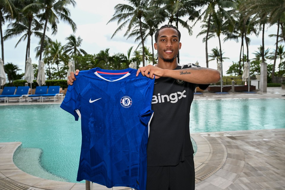 Joao Pedro holding a Chelsea jersey by a pool.
