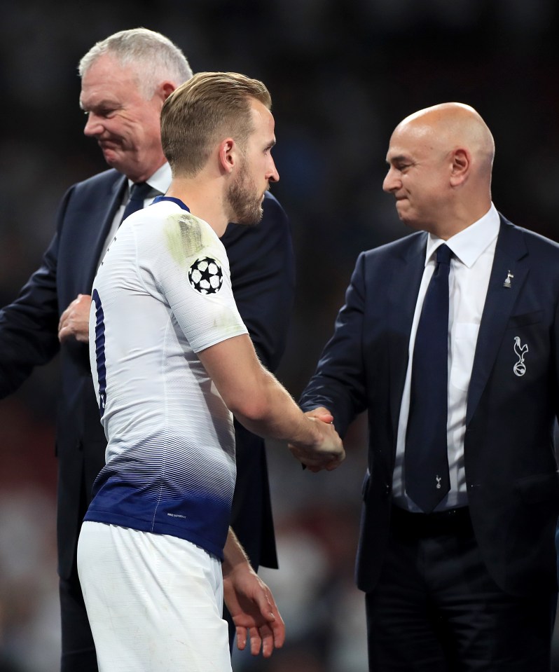 Harry Kane shaking hands with two men in suits.