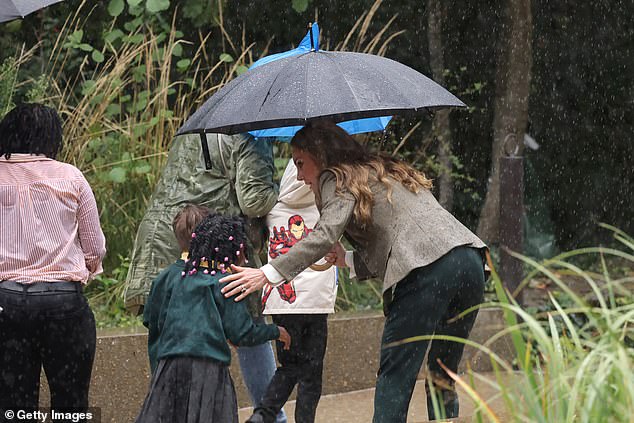 The Prince and Princess of Wales met with school pupils during their visit to the garden and Kate sweetly helped one child shelter under her umbrella as it started to pour with rain