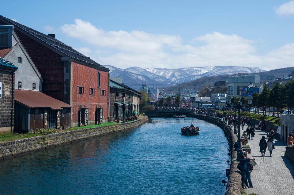 Otaru Canal in Hokkaido, Japan, with boats and people walking along the waterway.