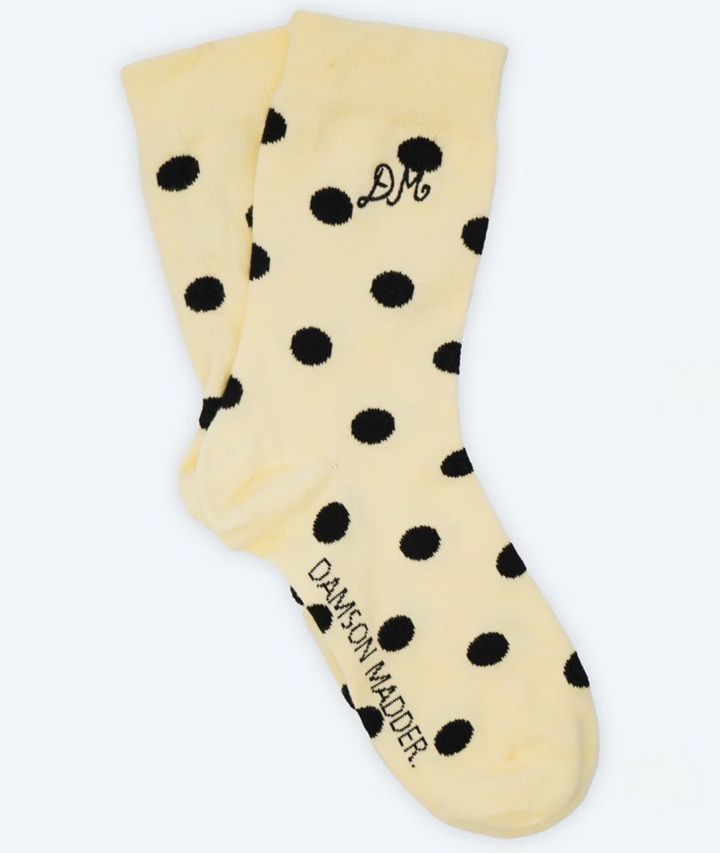 Pair of pale yellow socks with black polka dots and embroidered initials.