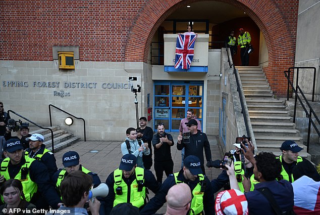 A protester (top centre) is arrested by police officers soon after attempting to hang a Union flag outside the council offices in Epping after a march from the Bell Hotel which houses asylum seekers, northeast of London, on August 31, 2025