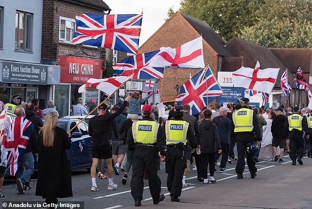 Demonstrators wave English and British flags as they protest outside The Bell Hotel
