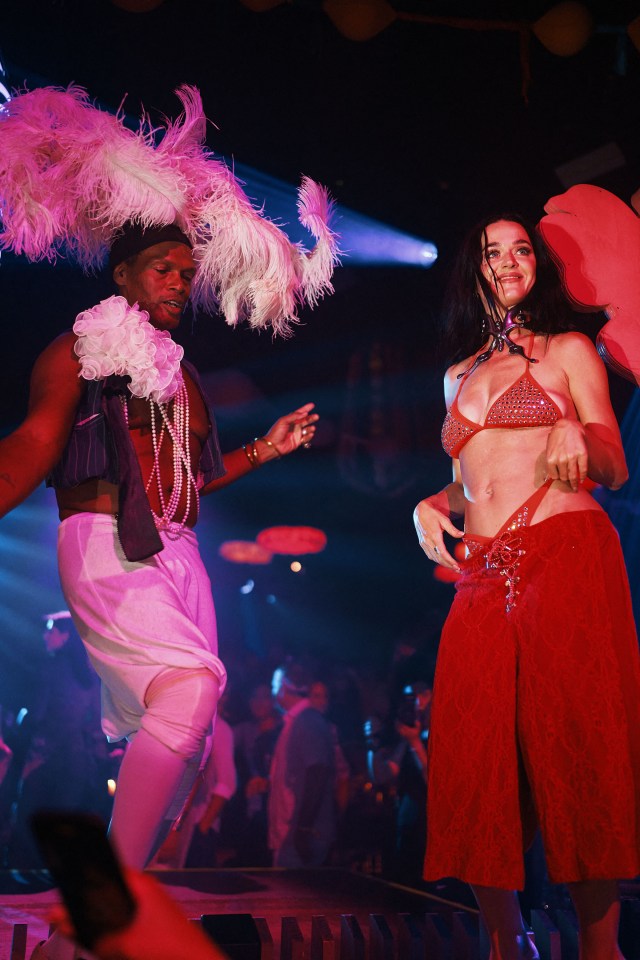 Katy Perry in a red bikini top and pants performing on stage.