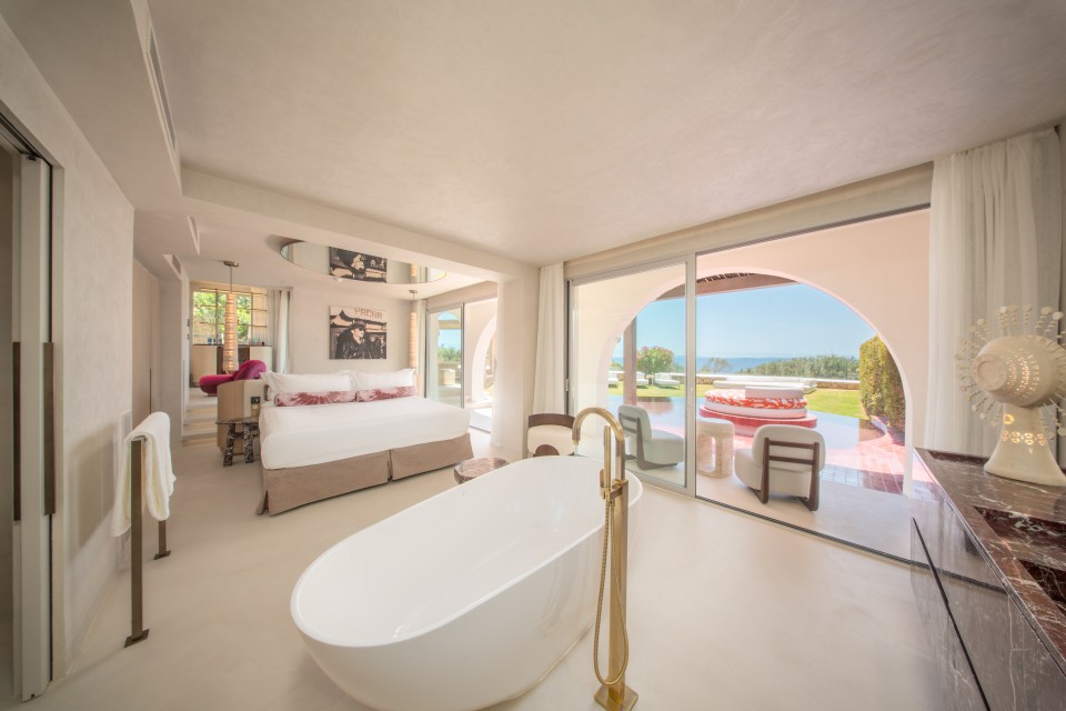Luxurious bedroom suite with freestanding bathtub and ocean view.