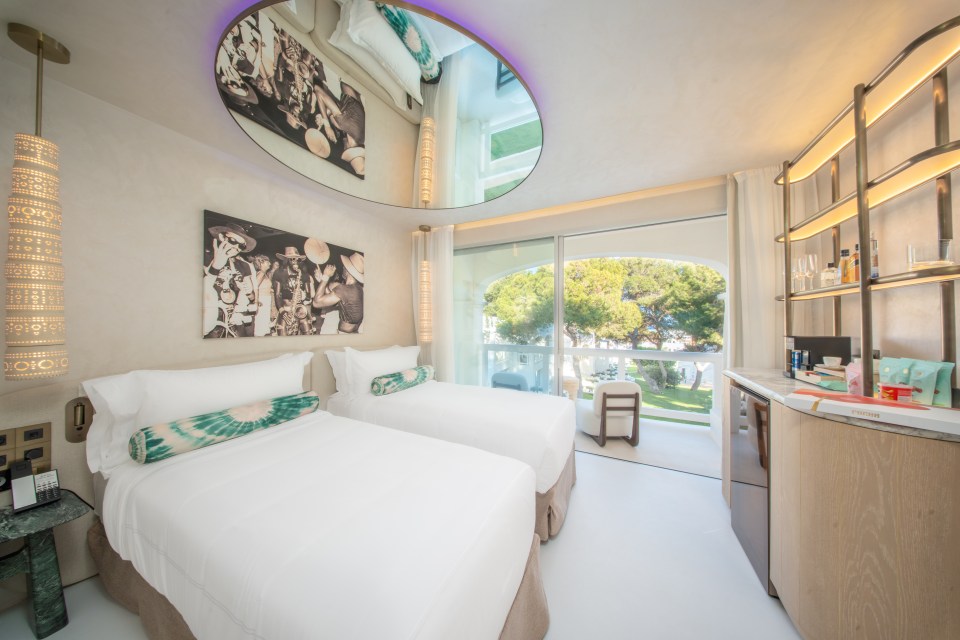 Hotel room with two twin beds, a balcony, and a mirrored ceiling.