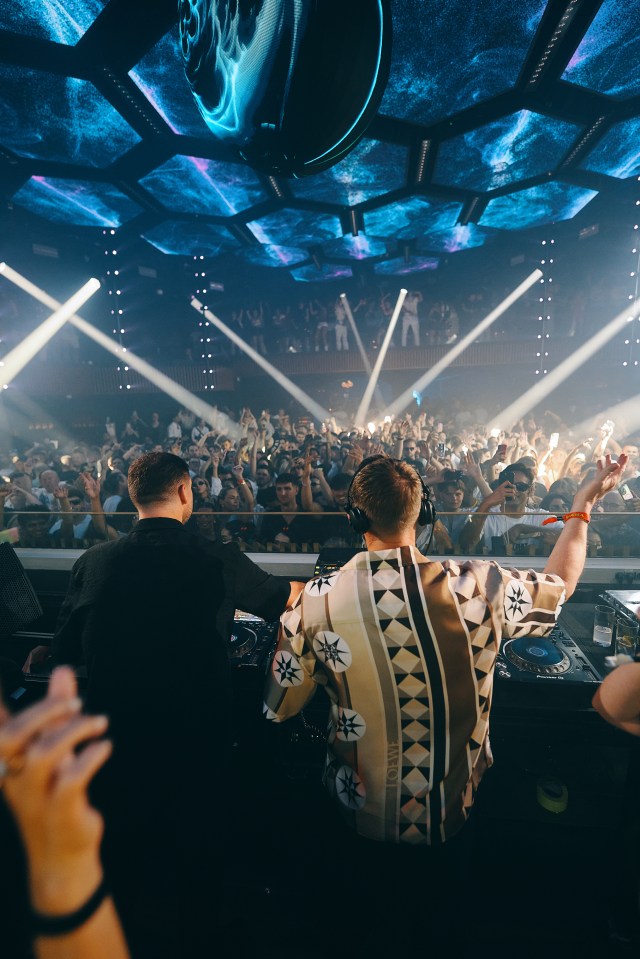 DJs performing at a crowded nightclub.