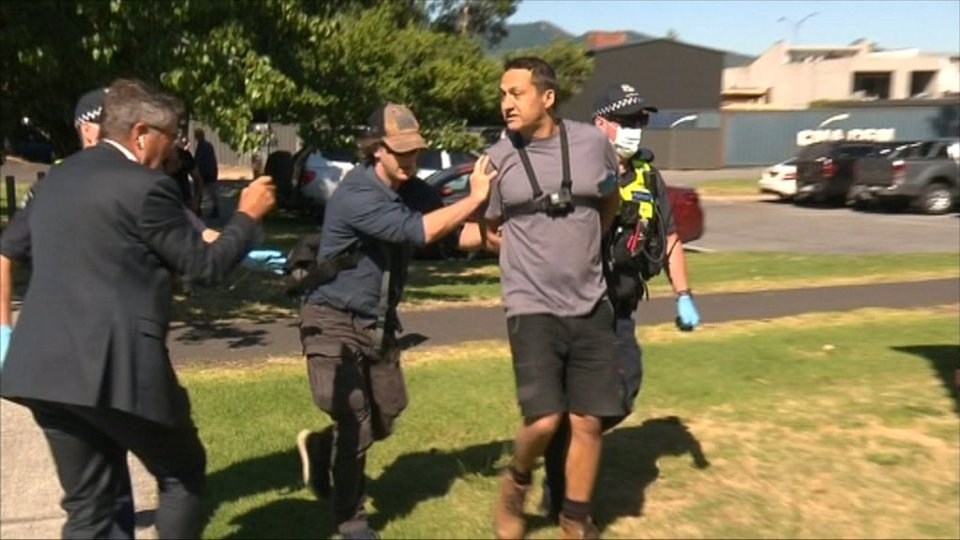 Police officers arresting a man.