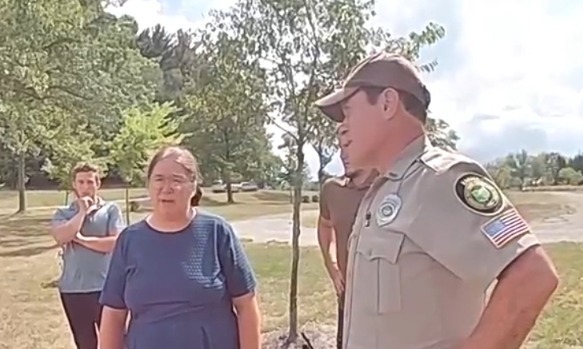 Amish woman speaking with a park ranger and another man.