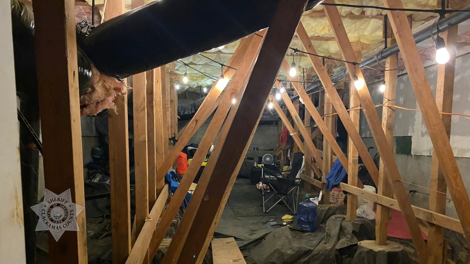 Inside of a condo crawl space with a bed, TVs, and other items, indicating someone was living there.