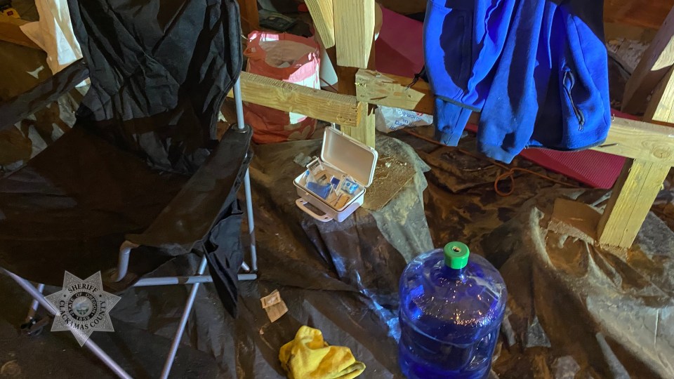 Contents of a condo crawl space where a man was living: a chair, first-aid kit, water jug, and clothing.