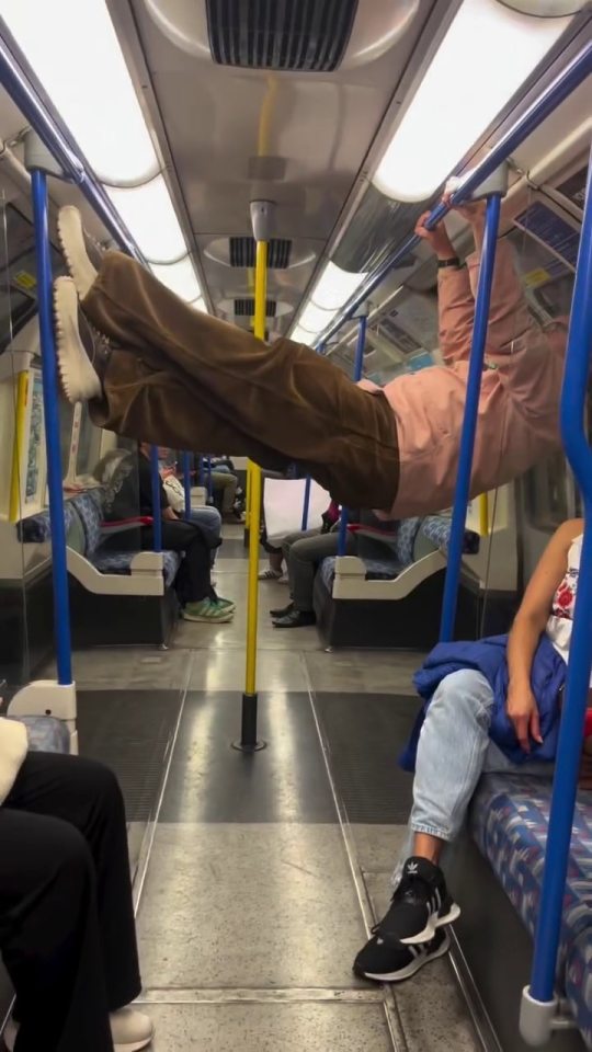 Man hanging from handrail on London Underground train.