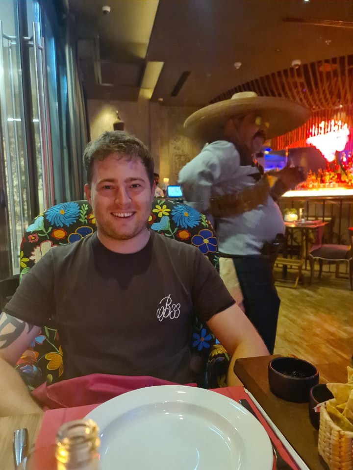 Man sitting at a restaurant table with a mariachi in the background.