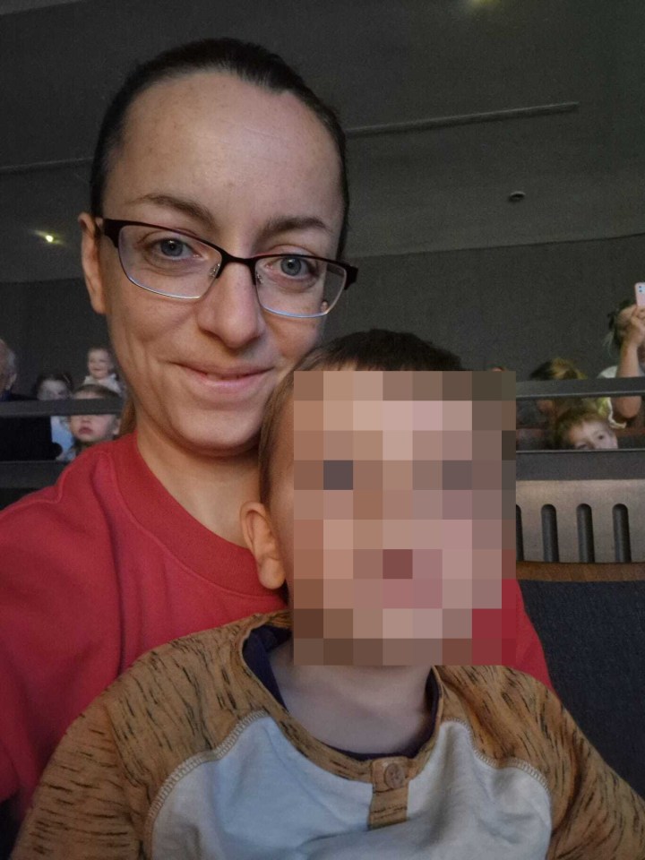 Woman with glasses holding a child whose face is blurred.