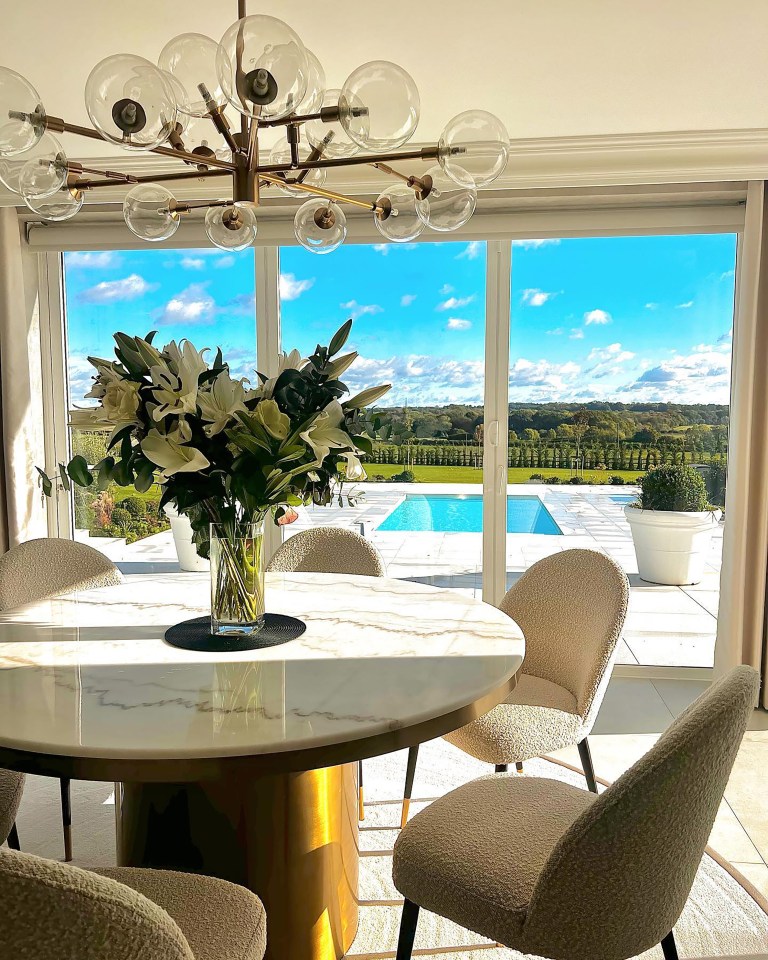 Dining room with marble table and chairs overlooking a pool.