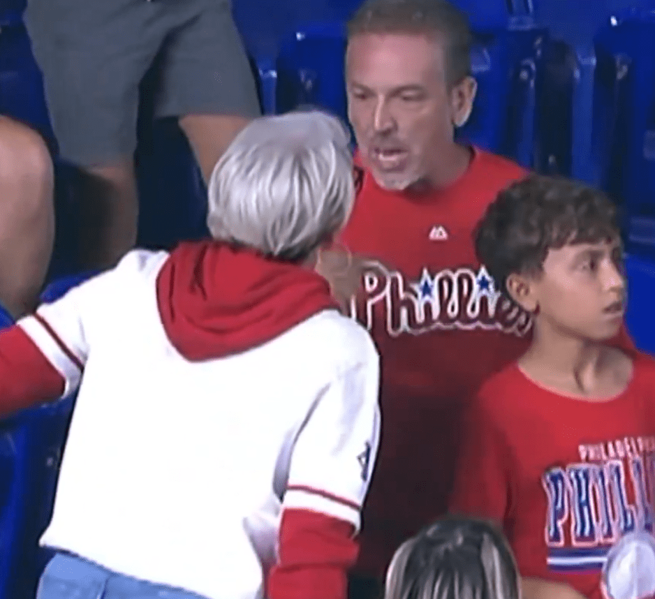 Woman taking a home run ball from a boy at a Phillies baseball game.