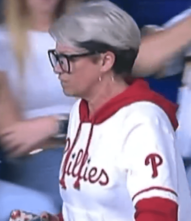 Woman in Phillies sweatshirt taking a home run ball from a child.