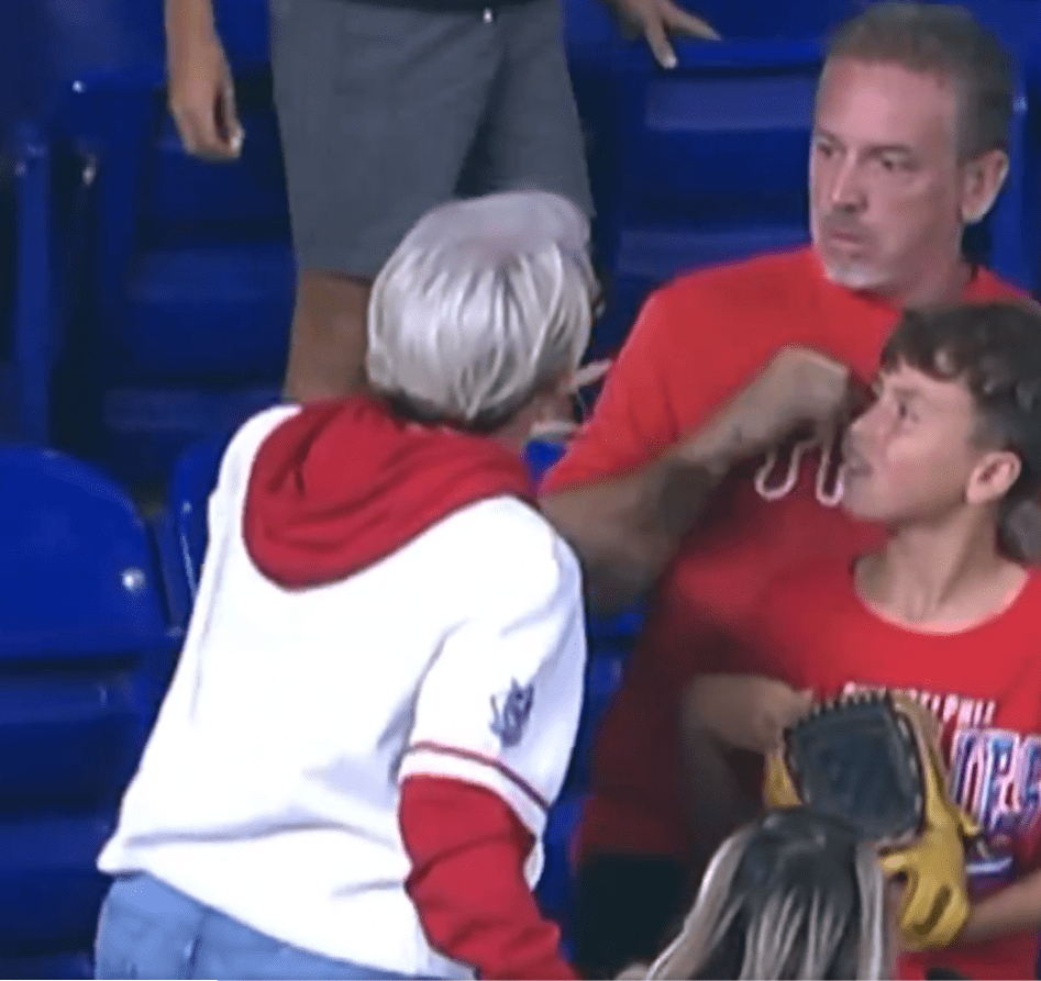 Woman taking baseball from boy at game.