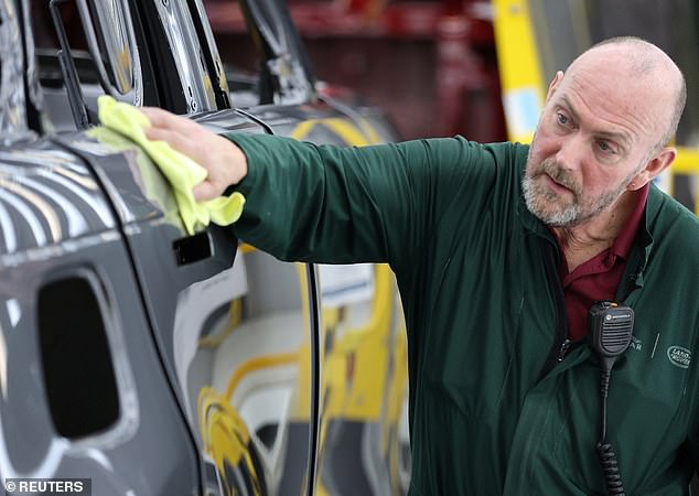 A member of staff checks the paintwork on Range Rover bodies as they pass through the paint shop at Jaguar Land Rover's factory in Solihull