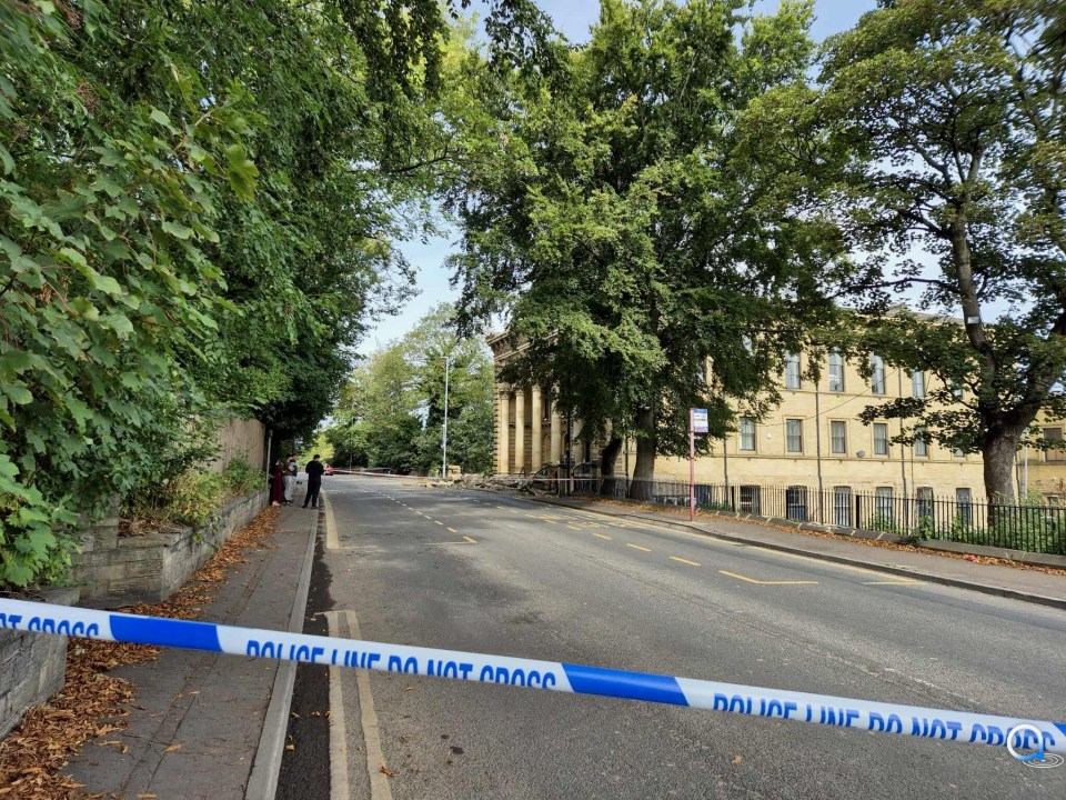 Collapsed building facade on a street, police tape visible.