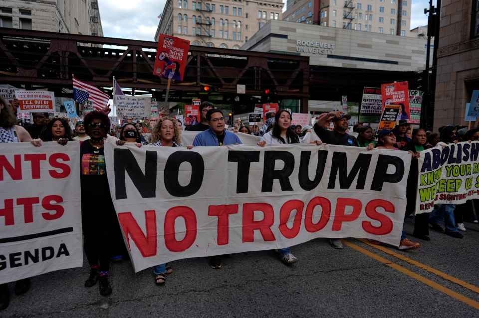 Protestors march with a banner reading "No Trump No Troops".