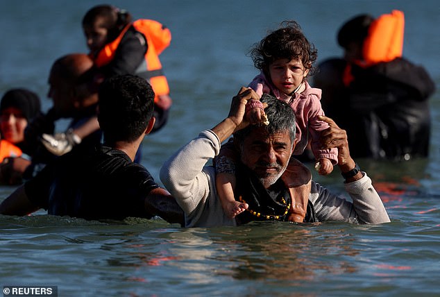 igrants wade through the sea in an attempt to board an inflatable dinghy leaving the coast of northern France to cross the English Channel to reach Britain, from the beach of Petit-Fort-Philippe in Gravelines, near Calais, France, August 25, 2025