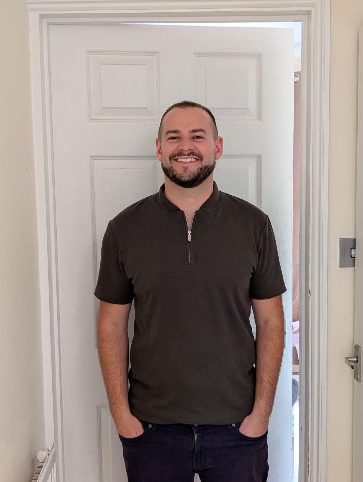 A man smiling and standing in a doorway.