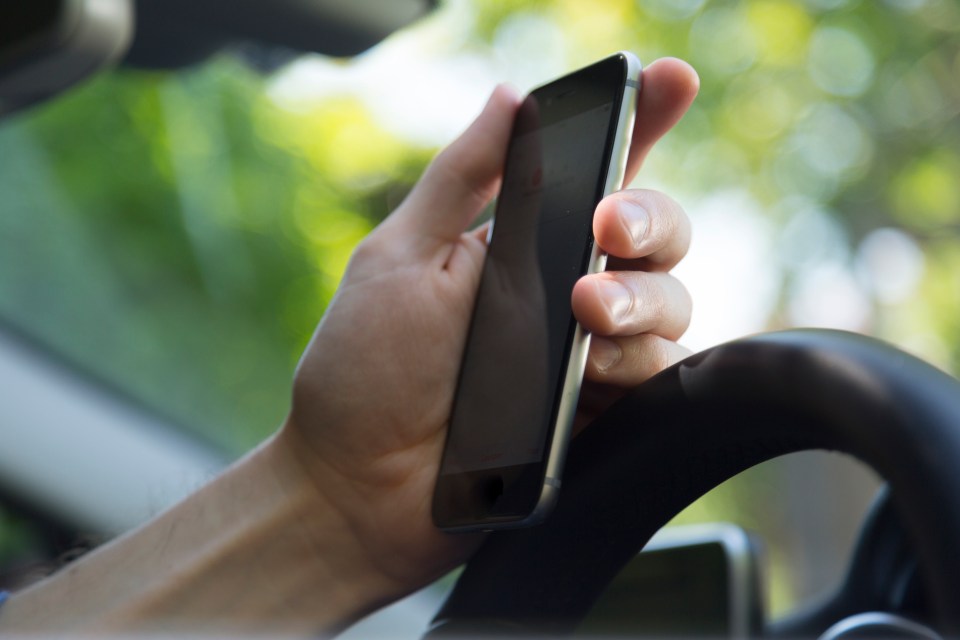 Hand holding a phone while driving.